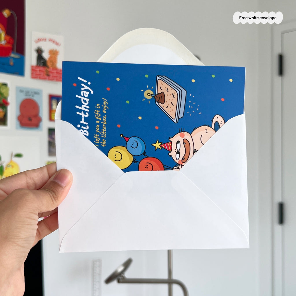 Hand holding a birthday card with cartoon design and free white envelope offer.