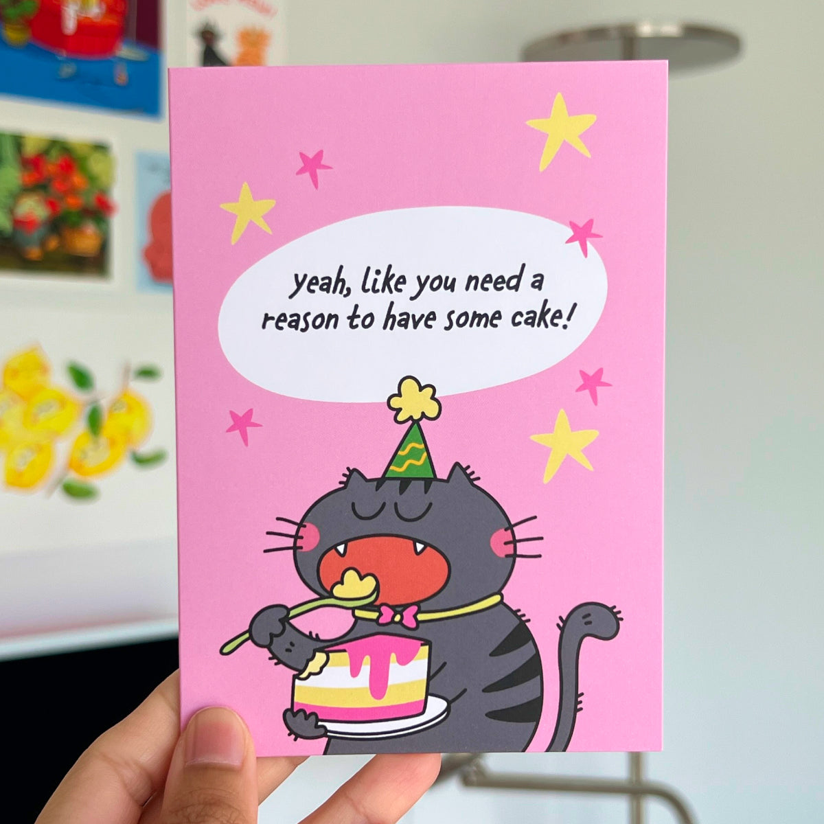 Card with a cartoon cat eating cake and stars on a pink background