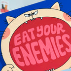 Cartoon character with a red mouth saying 'Eat your enemies' on a blue background