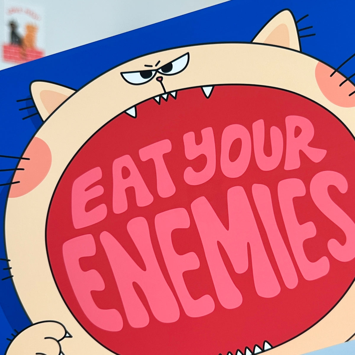 Cartoon character with a red mouth saying 'Eat your enemies' on a blue background