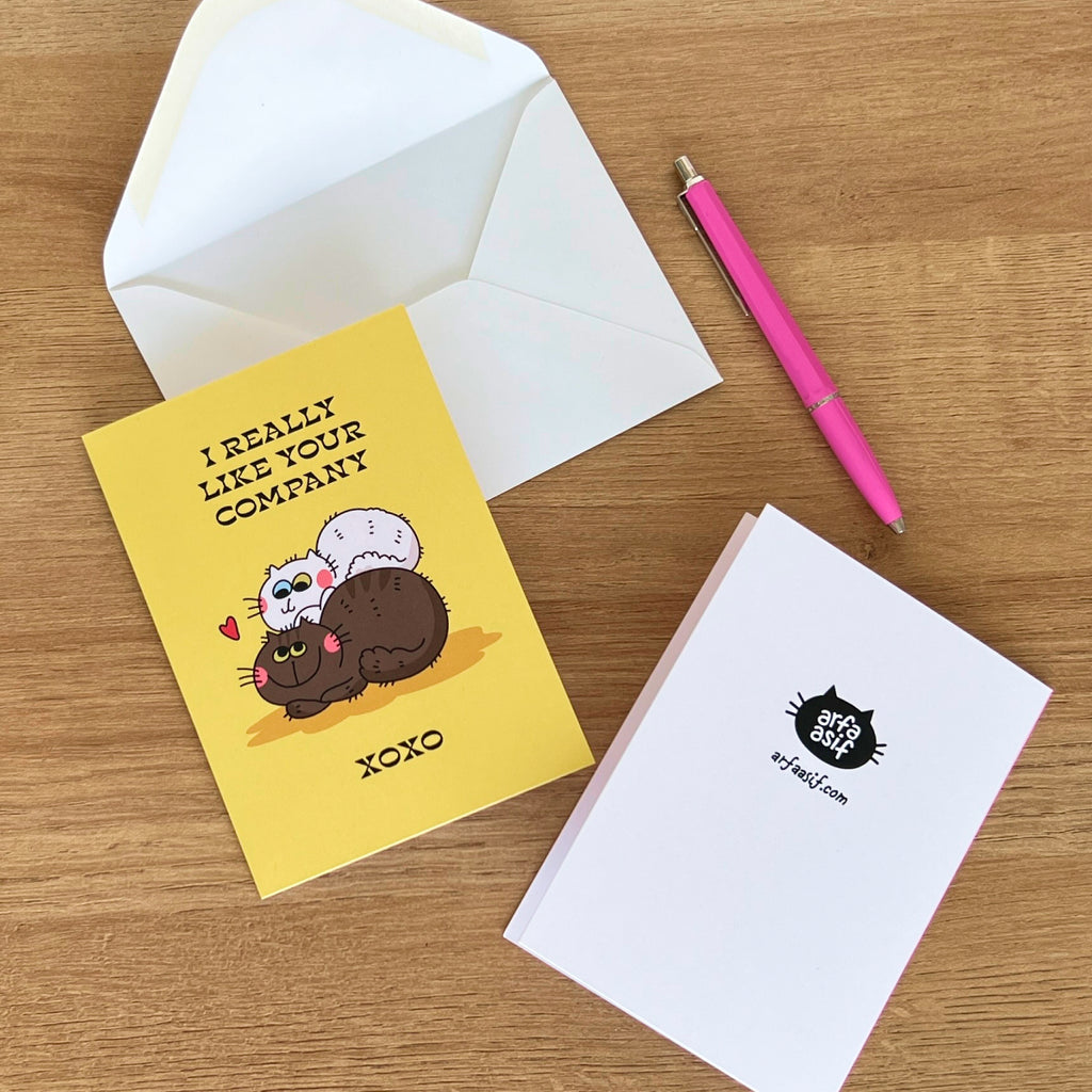 Greeting card with cartoon cats and envelope on a wooden surface