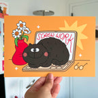 Cartoon cat on a laptop with 'Screw Work' text, held against an orange background.