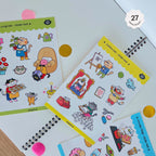 Set of colorful sticker sheets with fun cat characters on a white surface.