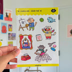 Sheet of 'Creative Cats' stickers held by a hand with a colorful background.