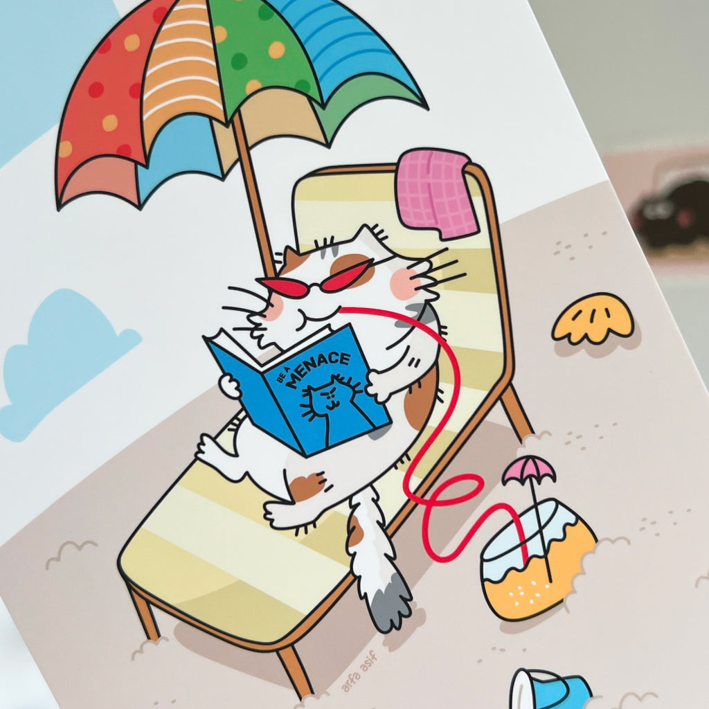 Cartoon cat reading a book under an umbrella on a beach chair.