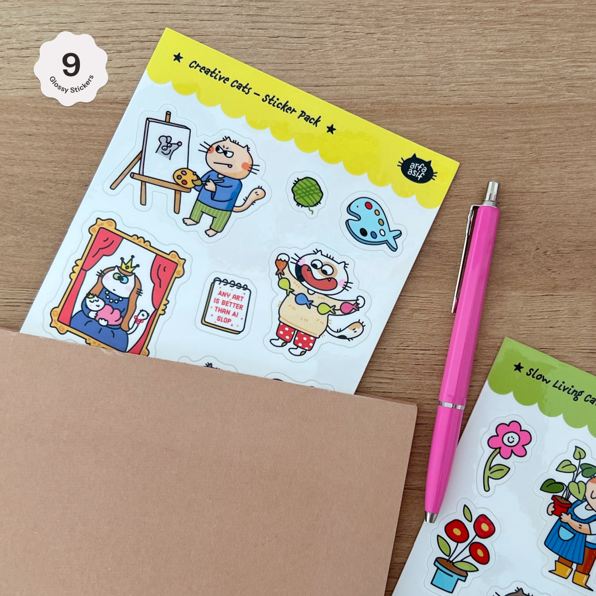 Sticker pack with cat characters on a wooden surface with a pen and paper.
