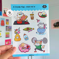Sticker pack with cat illustrations held by a hand against a colorful background
