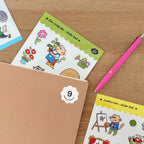 Cat-themed sticker packs on a wooden surface with a pink pen.
