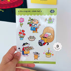 Sheet of cat stickers held by a hand with a white background
